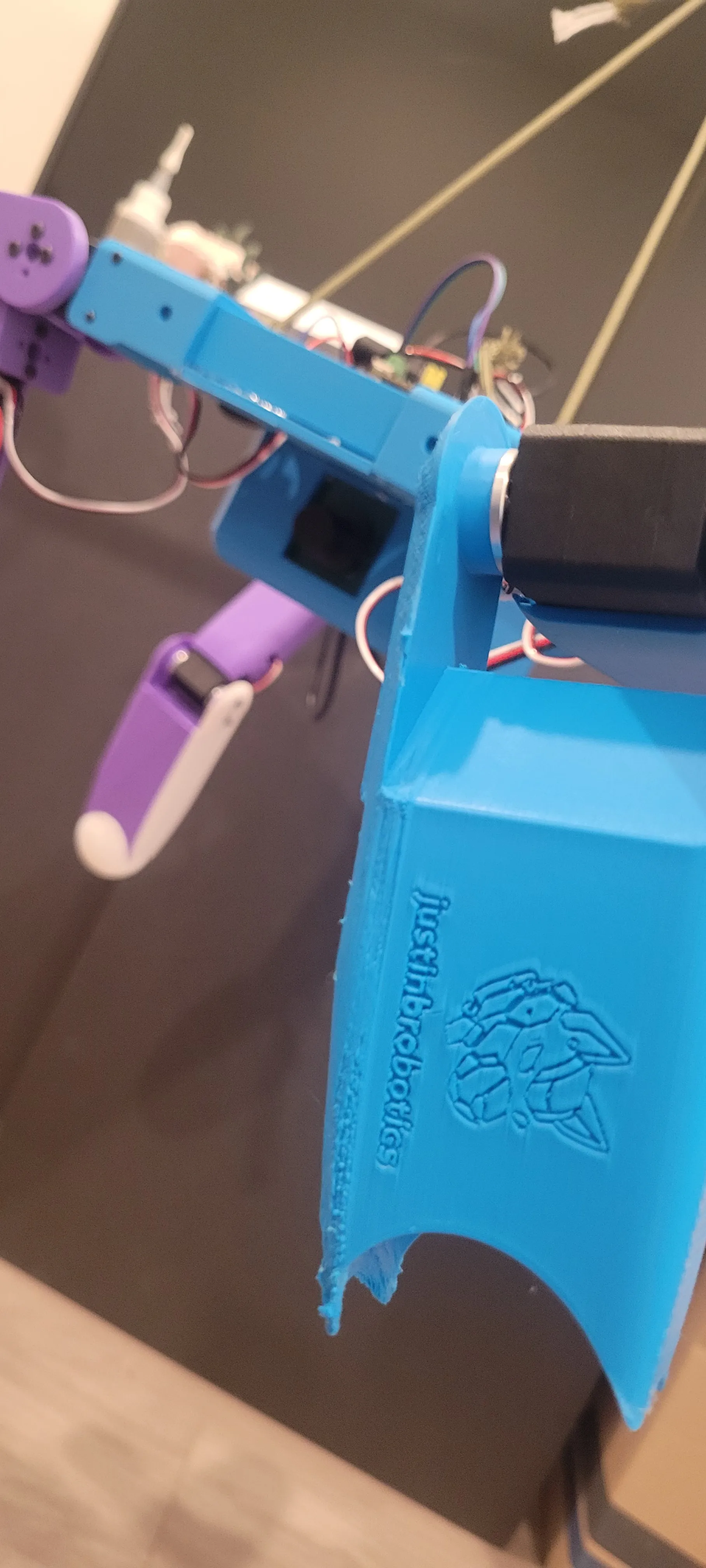 Close-up of the blue shell with the justinbrobotics wolf logo embossed straight into the print
