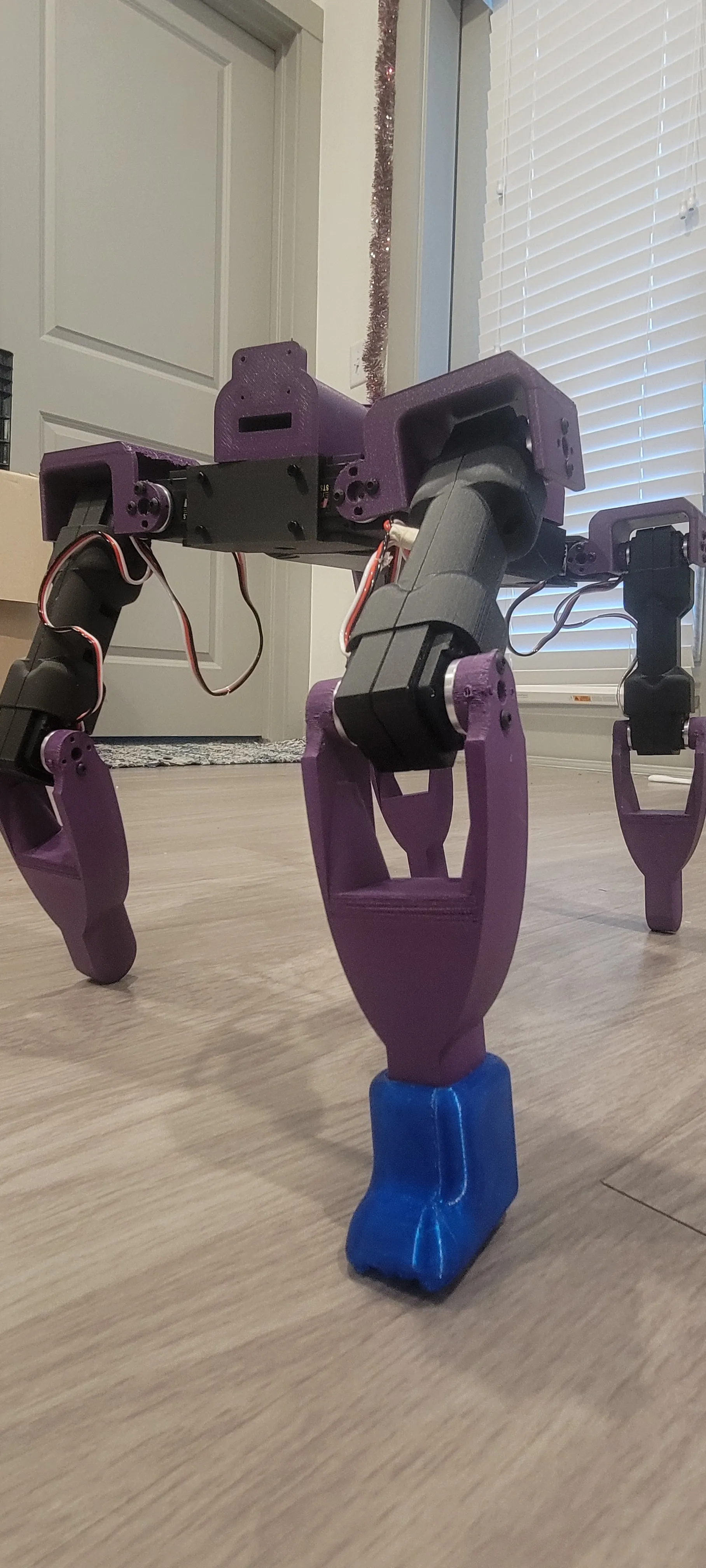 The next revision of Dog v3 standing — purple segmented legs, printed feet, servos at every joint